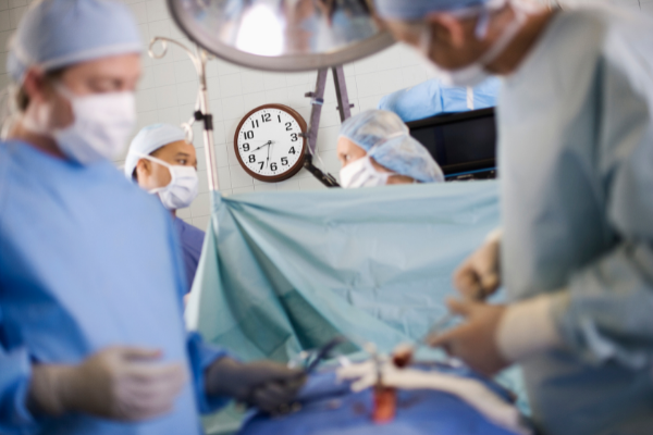 Image of clock in operating room time to answer question of whether computer assisted surgery increases or decreases operating room time